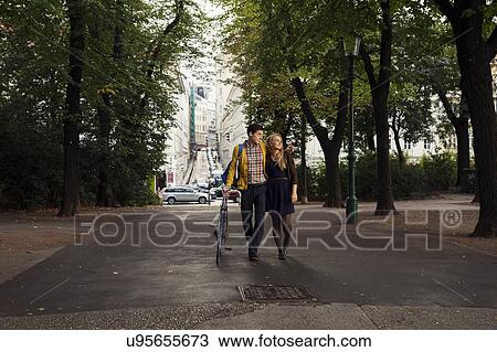 Young couple strolling in tree lined park View Large Photo Image Stock Image - Young couple strolling in tree lined park. Fotosearch