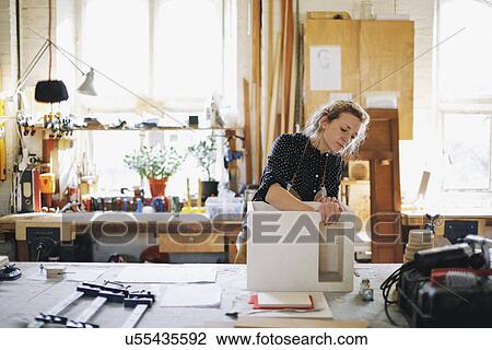 Stock Image - Young craftswoman checking component in pipe organ workshop. Fotosearch