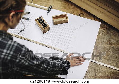 Stock Photo - Young craftswoman measuring blueprint in pipe organ workshop. Fotosearch