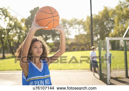 Picture - Young female basketball player holding up basketball. Fotosearch