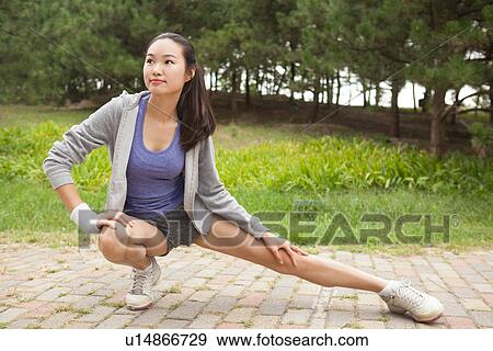 Young female runner stretching legs in park View Large Photo Image Stock Photo - Young female runner stretching legs in park. Fotosearch