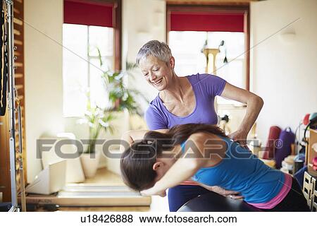 Young female student and tutor using pilates barrel in pilates gym View Large Photo Image Stock Photo - Young female student and tutor using pilates barrel in pilates gym. Fotosearch