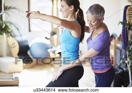 Young female student practicing with teacher in pilates gym View Large Photo Image Picture - Young female student practicing with teacher in pilates gym. Fotosearch