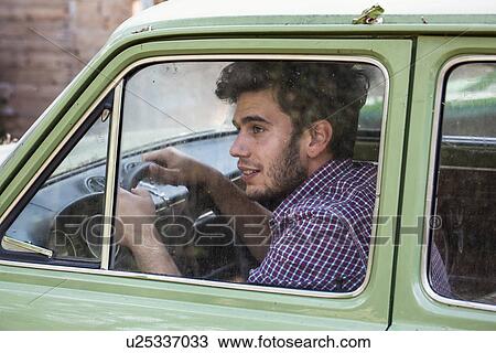 Stock Image - Young male farmer looking out of car window, Premosello, Verbania, Piemonte, Italy. Fotosearch