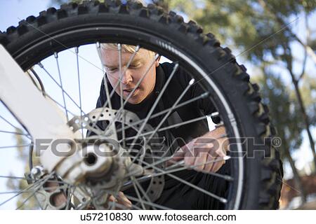 Young male motocross racer adjusting motorcycle wheel in forest View Large Photo Image Stock Image - Young male motocross racer adjusting motorcycle wheel in forest. Fotosearch