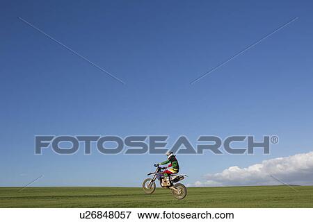 Young male motocross racer riding across field View Large Photo Image Stock Photo - Young male motocross racer riding across field. Fotosearch