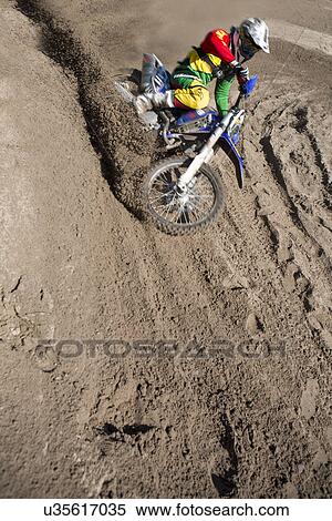 Young male motocross rider racing down mud hill View Large Photo Image Stock Photography - Young male motocross rider racing down mud hill. Fotosearch