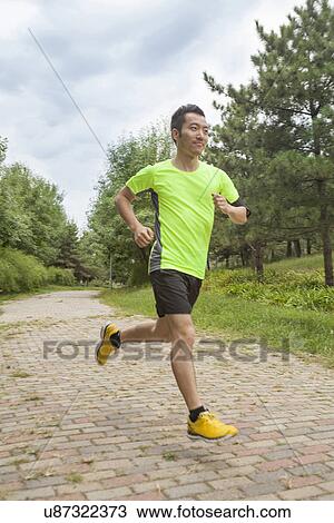 Stock Image - Young male runner running in park. Fotosearch