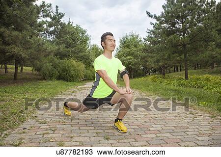 Young male runner stretching legs in park View Large Photo Image Stock Image - Young male runner stretching legs in park. Fotosearch