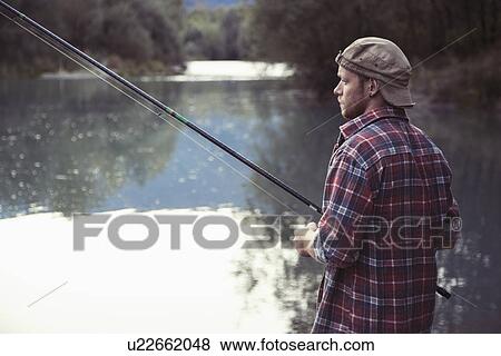 Stock Photo - Young man fishing in lake, Premosello, Verbania, Piemonte, Italy. Fotosearch