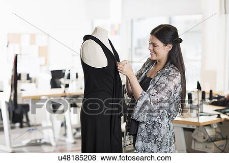Young seamstress fitting dress on tailors dummy in workshop View Large Photo Image Stock Photo - Young seamstress fitting dress on tailors dummy in workshop. Fotosearch