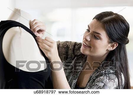 Young seamstress pinning dress on tailors dummy in workshop View Large Photo Image Stock Photo - Young seamstress pinning dress on tailors dummy in workshop. Fotosearch