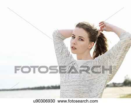 Young woman adjusting ponytail View Large Photo Image Stock Image - Young woman adjusting ponytail. Fotosearch