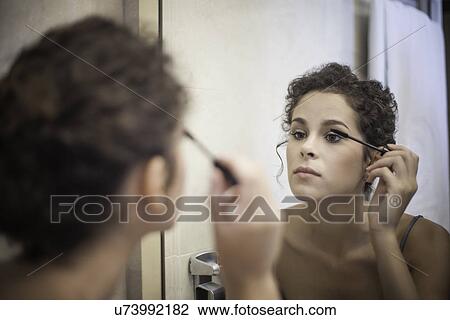 Stock Image - Young woman applying mascara. Fotosearch