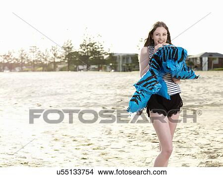 Young woman blowing up inflatable on beach View Large Photo Image Picture - Young woman blowing up inflatable on beach. Fotosearch