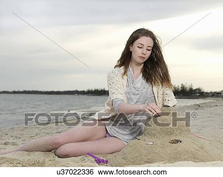 Young woman building sandcastle View Large Photo Image Stock Photograph - Young woman building sandcastle. Fotosearch