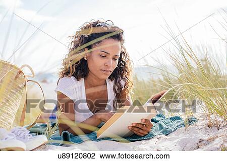 Young woman cross reading a book in beach dunes, Tuscany, Italy View Large Photo Image Stock Image - Young woman cross reading a book in beach dunes, Tuscany, Italy. Fotosearch