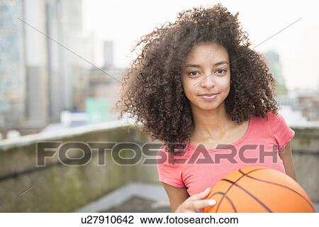 Stock Image - Young woman holding basketball. Fotosearch
