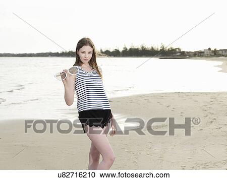 Young woman holding oversize sunglasses on beach View Large Photo Image Stock Image - Young woman holding oversize sunglasses on beach. Fotosearch