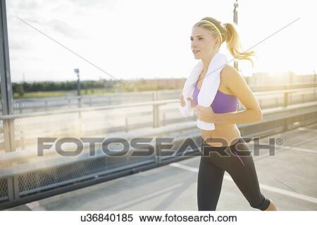 Stock Photography - Young woman jogging with towel. Fotosearch