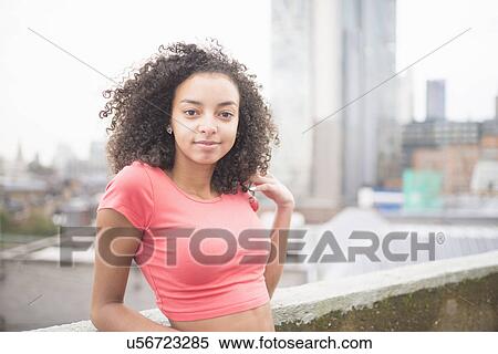 Stock Photography - Young woman leaning against wall. Fotosearch