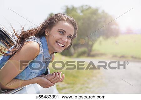 Young woman leaning out of car window on road trip View Large Photo Image Stock Image - Young woman leaning out of car window on road trip. Fotosearch