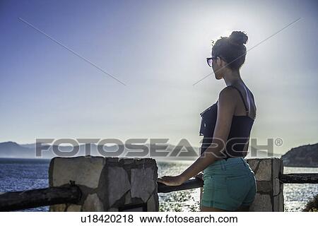 Stock Photo - Young woman looking at view of the sea. Fotosearch