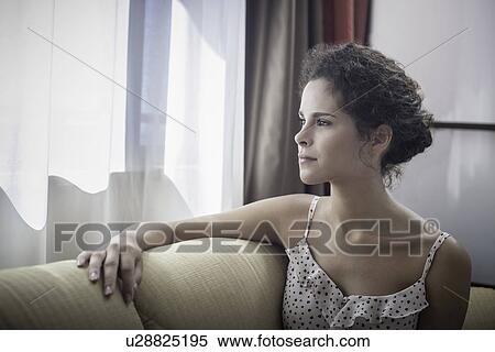 Stock Photography - Young woman looking out of window. Fotosearch