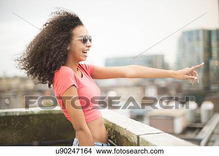 Picture - Young woman on rooftop, pointing. Fotosearch