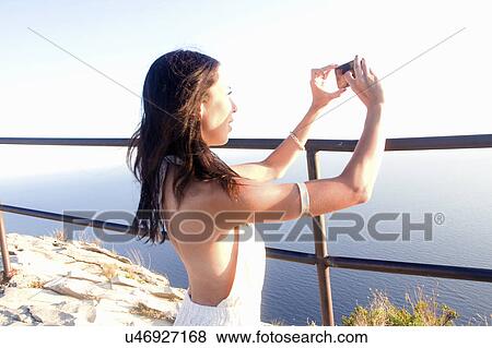 Young woman photographing sea on smartphone, Marseille, France View Large Photo Image Stock Photo - Young woman photographing sea on smartphone, Marseille, France. Fotosearch