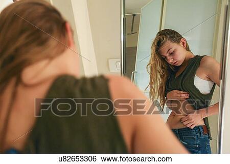 Stock Photograph - Young Woman pinching her waist. Fotosearch