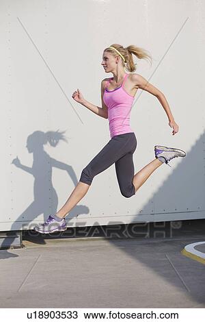 Stock Image - Young woman running and jumping. Fotosearch