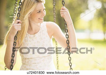 Young woman sitting on park swing View Large Photo Image Stock Image - Young woman sitting on park swing. Fotosearch