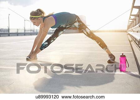 Stock Image - Young woman stretching legs. Fotosearch