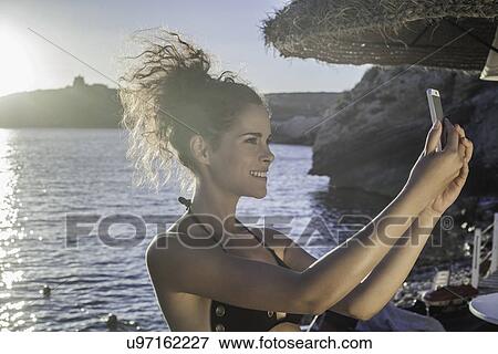 Stock Photo - Young woman taking selfie. Fotosearch