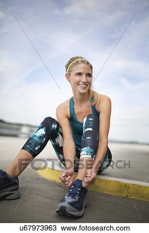 Stock Image - Young woman tying trainers. Fotosearch