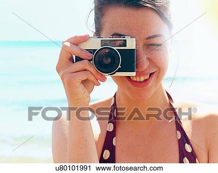 Young woman using camera on beach View Large Photo Image Stock Image - Young woman using camera on beach. Fotosearch