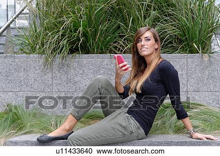 Stock Image - Young woman using mobile phone. Fotosearch