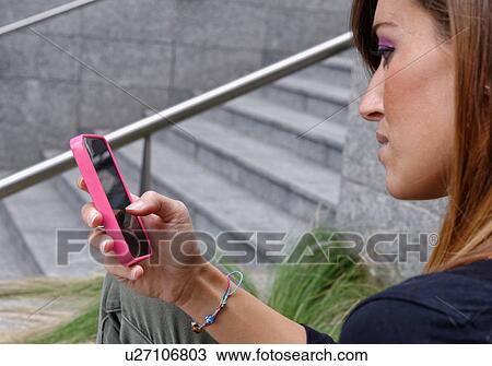 Stock Image - Young woman using mobile phone. Fotosearch