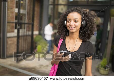 Stock Photo - Young woman using mp3 player. Fotosearch