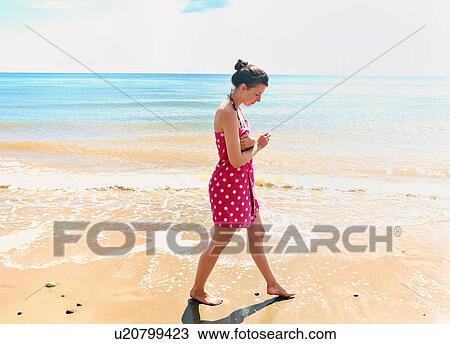 Young woman walking on beach View Large Photo Image Stock Image - Young woman walking on beach. Fotosearch