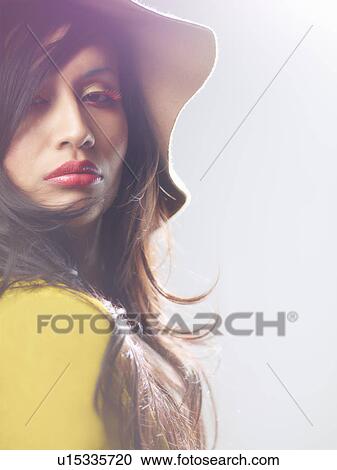 Stock Image - Young woman wearing hat, backlit. Fotosearch