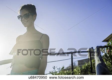 Young woman wearing sunglasses in sunlight View Large Photo Image Stock Image - Young woman wearing sunglasses in sunlight. Fotosearch