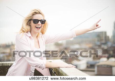 Young woman wearing sunglasses, pointing View Large Photo Image Stock Image - Young woman wearing sunglasses, pointing. Fotosearch