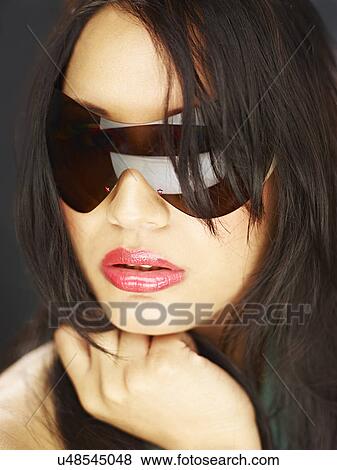 Stock Photo - Young woman wearing sunglasses. Fotosearch