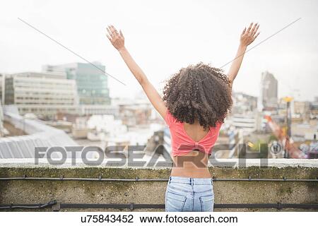 Young woman with arms raised, rear view View Large Photo Image Stock Image - Young woman with arms raised, rear view. Fotosearch