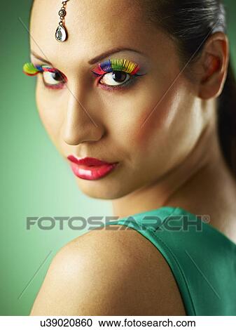 Stock Image - Young woman with jewel head accessory and coloured eyelashes. Fotosearch