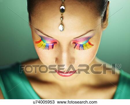 Stock Image - Young woman with jewel head accessory and coloured eyelashes. Fotosearch