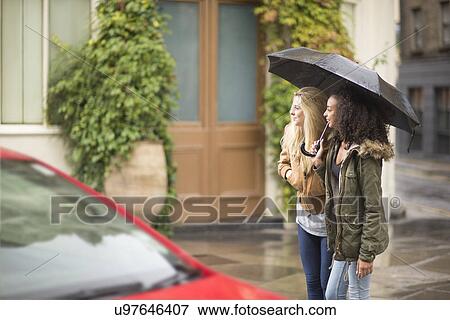 Young women using umbrella View Large Photo Image Stock Photo - Young women using umbrella. Fotosearch
