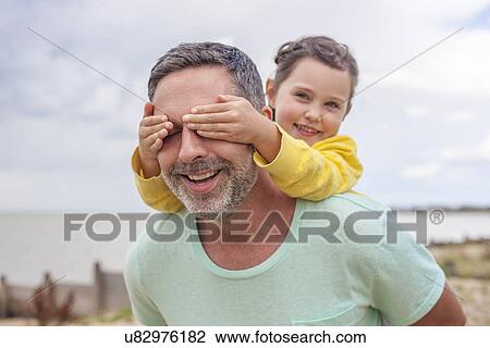 Stock Image - Daughter covering father's eyes. Fotosearch